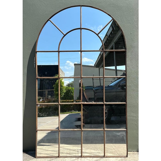 This monumental arched windowpane mirror is a commanding architectural statement piece, perfect for adding depth and light...