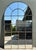 This monumental arched windowpane mirror is a commanding architectural statement piece, perfect for adding depth and light...