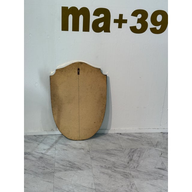 A classic Italian wall mirror in an elegant shield shape, framed with a slender brass border. Its gently curved silhouette...