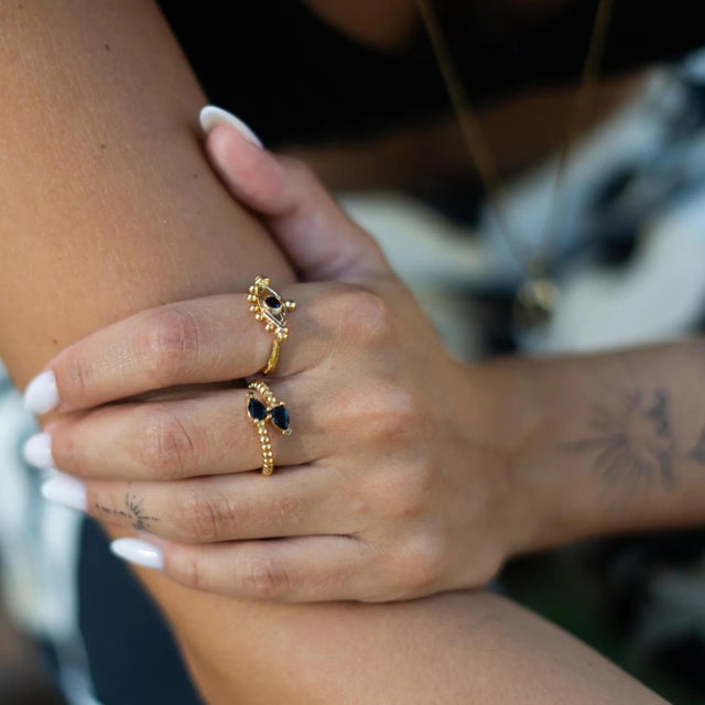The Mystic Black Onyx Evil Eye Gold Adjustable Band Ring is a bold talisman of grounding and protection. The deep black...