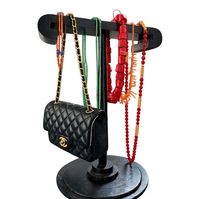 A striking handcrafted black-painted wood display stand whose bold architectural silhouette recalls the glamorous...