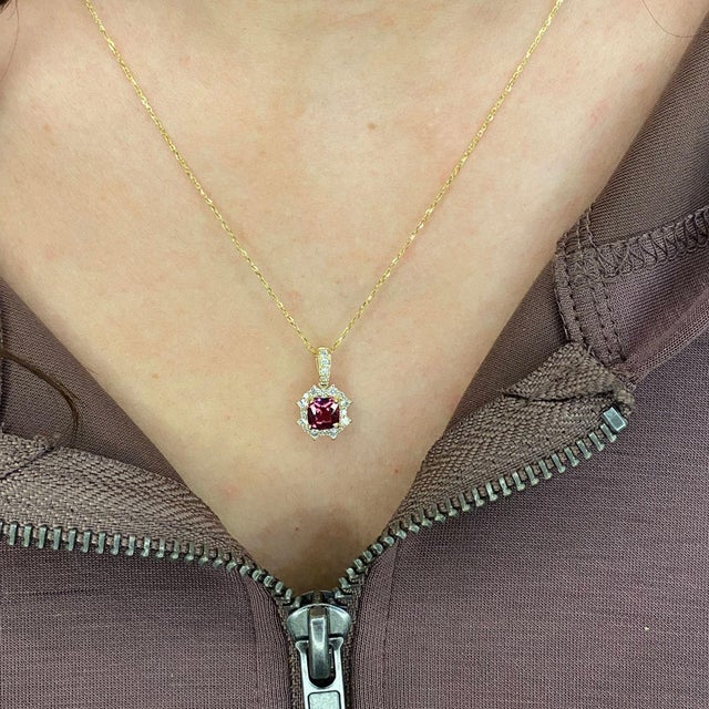 A beautiful pendant features a 1.03-carat rhodolite gemstone with a halo of natural earth-mined diamonds and a diamond-...