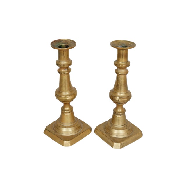 A pair of antique brass candlestick holders. Traditional baluster turned columns support simple capitals and finish with...