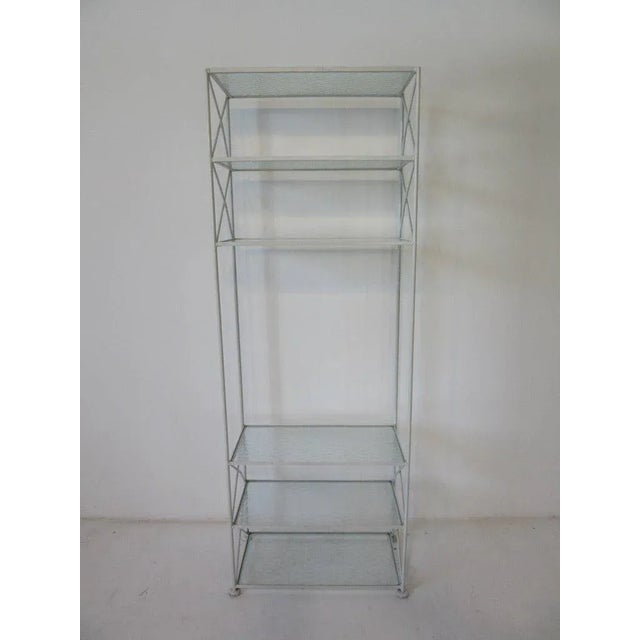 A hard to find satin white iron etagere or bookcase with pebbled glass shelves and X cross bracing manufactured by the...
