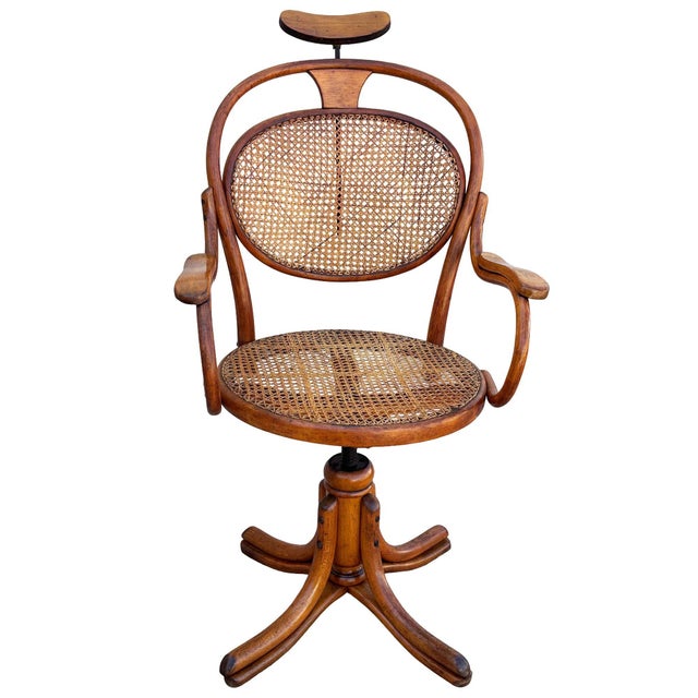 Late Victorian German bent oak barbers chair with a cane seat featuring graceful, fluid curves and integrated adjustable...