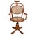 Late Victorian German bent oak barbers chair with a cane seat featuring graceful, fluid curves and integrated adjustable...
