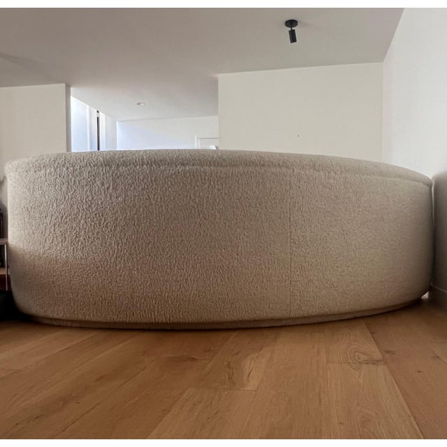 A vintage biomorphic curvy sofa, late 20th century. Upholstered in an off-white shearling bouclé, this piece represents...