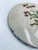 A decorative wall plate of Italian origin, made of high-quality ceramic. The plate features a botanical illustration...