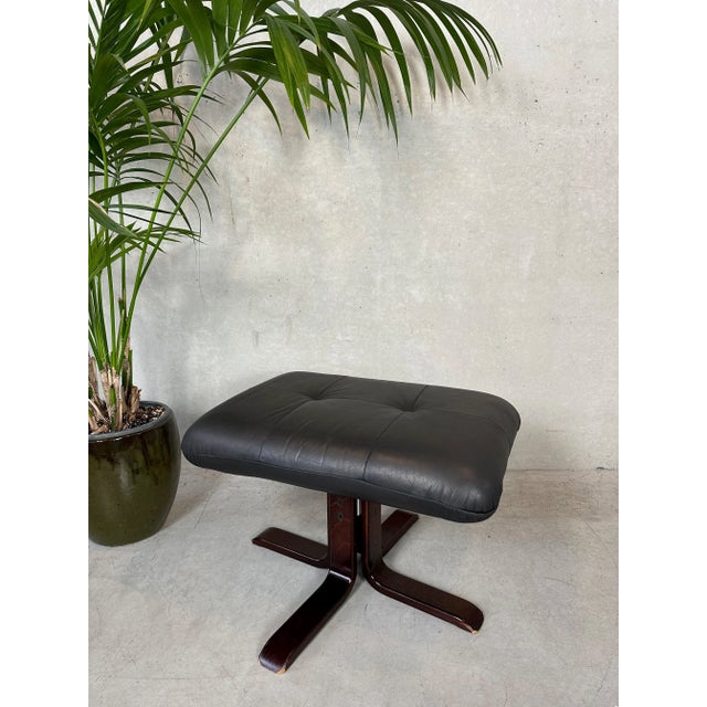 Vintage ottoman/footrest. Black leather on a plywood base. Normal signs of use. Legs are adjustable. Seat cushion rotating...
