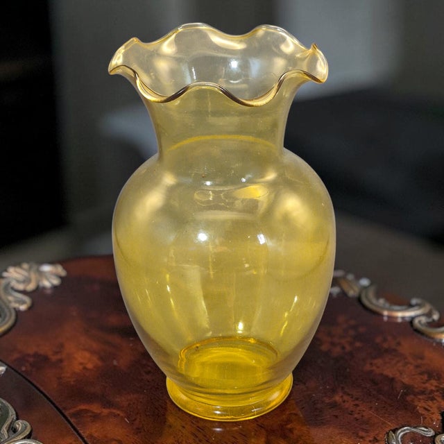 This vintage amber yellow hand-blown glass vase stands at 10.5 inches tall with a ruffled rim, adding a unique and...
