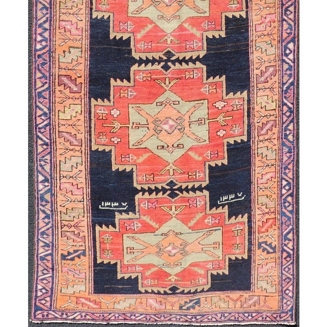 This antique Persian Azerbaijan styled runner has been hand-knotted in wool. The rug features a sub-geometric medallion...