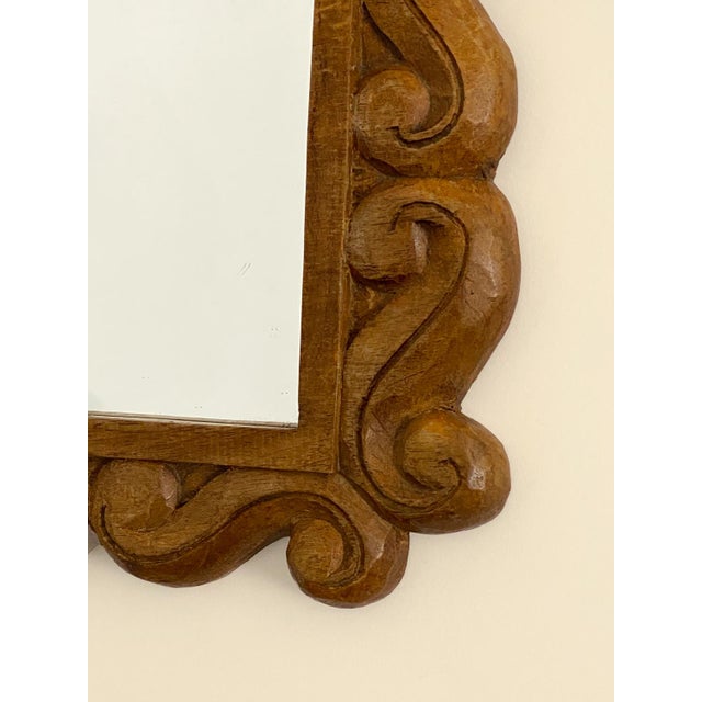 Mirror with a carved wooden frame, adorned with a relief scrollwork design around its entire perimeter. Its symmetrical...