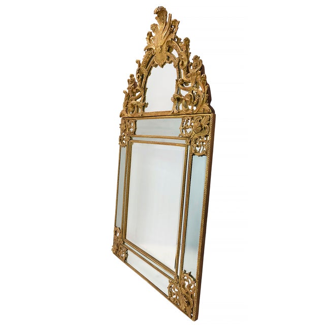 French carved giltwood wall mirror, from 18th century Régence Period. The frame is decorated with detailed foliate designs...