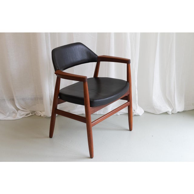 Danish Mid-century Modern arm chair in solid teak with original black leather upholstery designed in 1957. Round tapered...