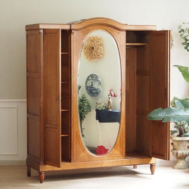 Three-door oak wardrobe with an oval bevelled mirror, stylistically situated between late Art Nouveau and reform-oriented...