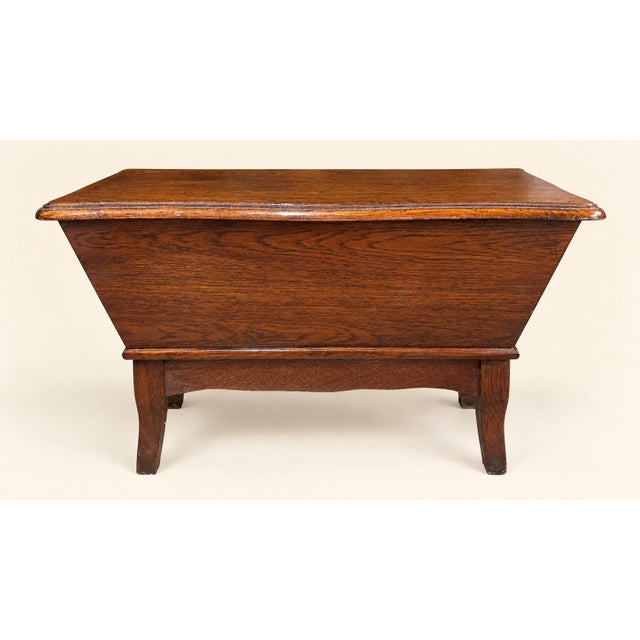 A solid oak chest from the english arts & crafts period, early 20th century. Its inverted trapezoidal shape—wider at the...