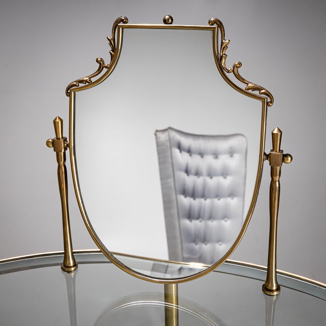 Elegant kidney-shaped brass vanity table featuring two glass surfaces, partially frosted and adorned with a star-shaped...