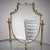 Elegant kidney-shaped brass vanity table featuring two glass surfaces, partially frosted and adorned with a star-shaped...