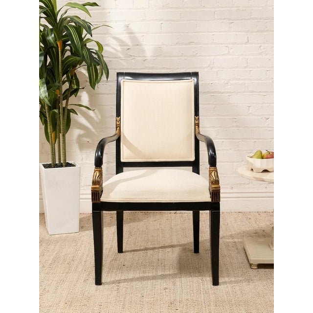 An elegant vintage armchair with a tall upholstered back, generously cushioned seat, and a dramatic black frame accented...