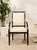 An elegant vintage armchair with a tall upholstered back, generously cushioned seat, and a dramatic black frame accented...