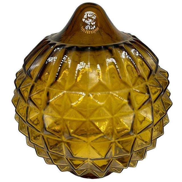 Mid-century Mediterranean-style yellow hand-blown amber glass globe features a glass globe with beveled pyramids around...