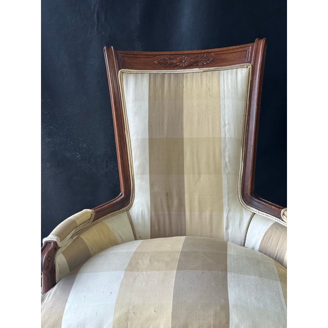 Generously scaled late 19th- to early 20th-century French Louis XV–style bergère armchair crafted in carved walnut. The...