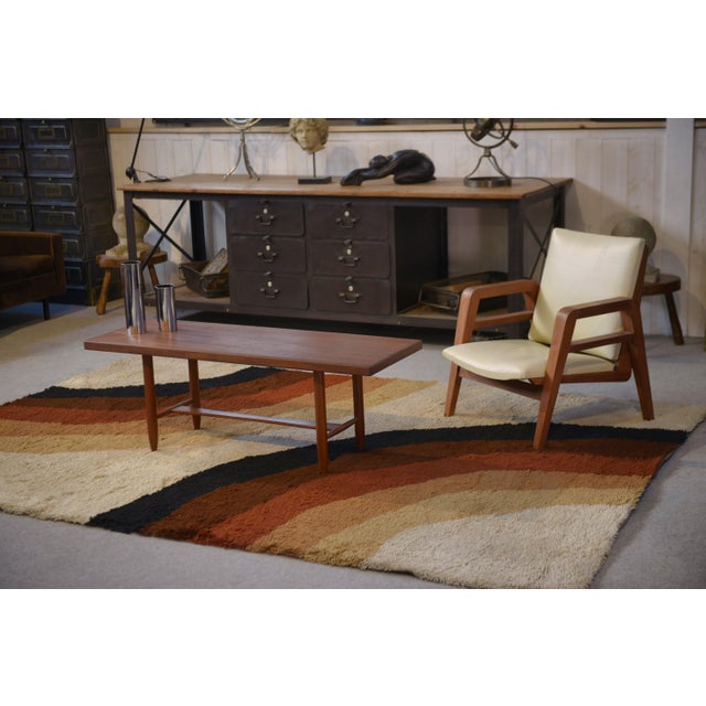 A Scandinavian teak coffee table from the 1960s, with a clean and timeless design. The rectangular top is thin, with...