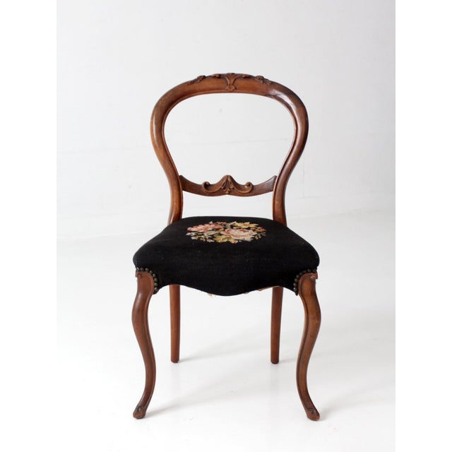 An antique late 19th-century Victorian balloon-back chair with a carved wood frame, cabriole front legs, and black floral...