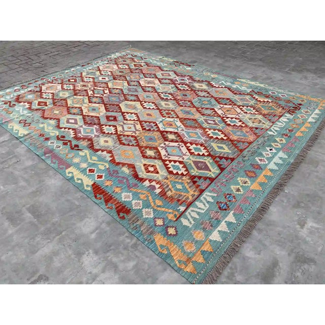 Transform your space with this striking Afghan Kilim rug, featuring a vibrant array of geometric patterns in rich hues of...