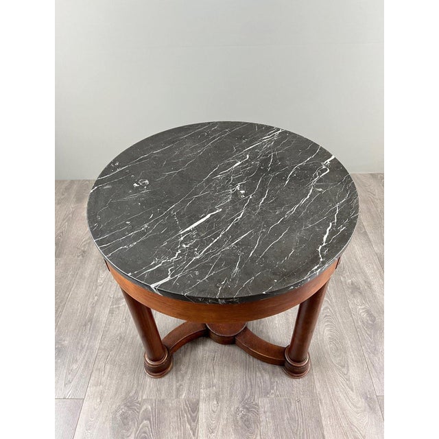 Mahogany side table with black marble top – Restoration period An elegant mahogany side table resting on three column legs...