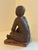 Seated ceramic figure of young boy on wooden stand. Could be used as a paper weight or a bookend, or as an accent piece.