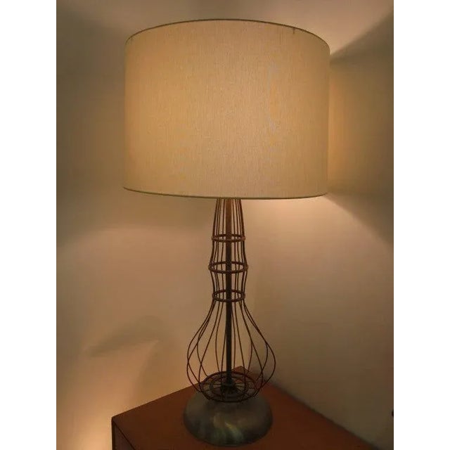 A industrial open shaped table lamp body made of brass and sitting on a heavy spun aluminum base topped by a wide rimmed...