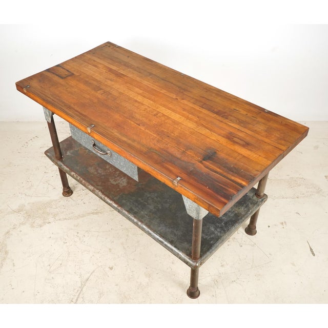 Early 20th century Industrial style heavy duty workbench with a solid wood tabletop, a galvanized steel drawer, lower...