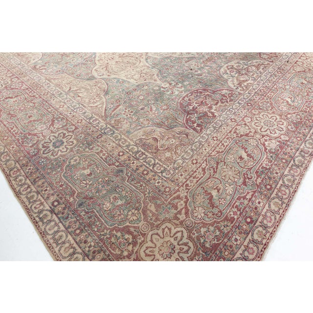 A hand-knotted wool antique Persian Kirman rug dating back to 1920. The main field features a grid of medallions with...