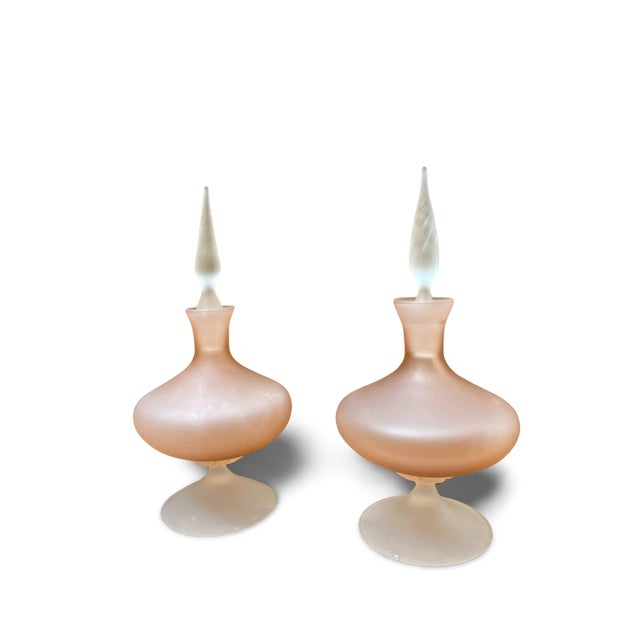 Pair of satin-finished blown glass perfume bottles in a powdery pink hue with an opaline gradient, resting on flared...