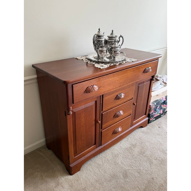 This is a solid cherry wood sideboard featuring a large top drawer spanning the width of the piece, flanked by two side...