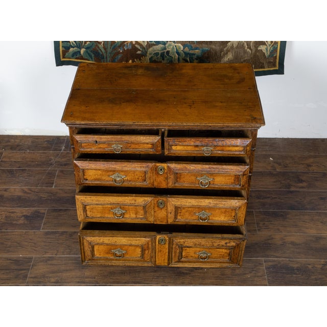 An English George III period oak commode from the early 19th century, with five graduating drawers, raised panels, brass...