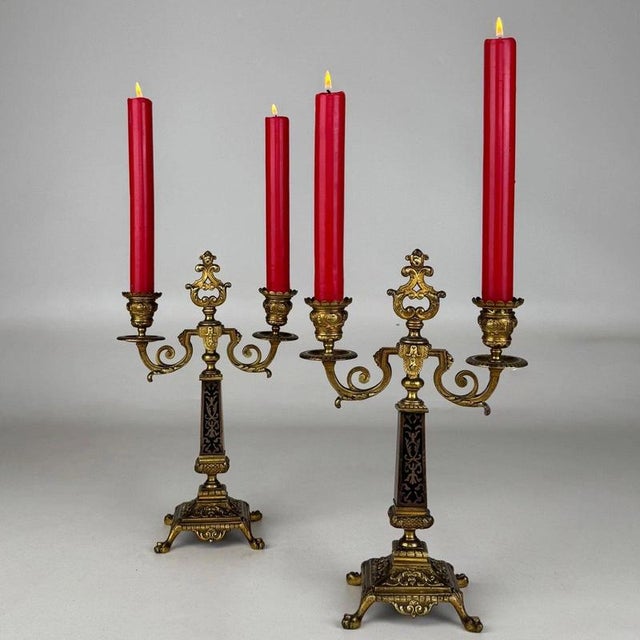 An elegant pair of 19th-century French candelabra, finely crafted in brass and distinguished by their contrasting ebony...