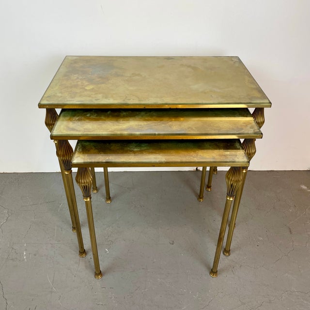 Elegant mid-century neoclassical set of three nesting tables crafted in gilt brass, featuring slender fluted legs and...