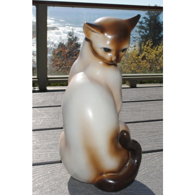 This vintage ceramic siamese cat is a bit aloof in is pose. It is a seal point siamese with dark eyes.