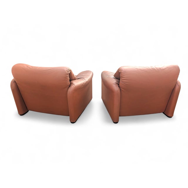 These two iconic tan leather armchairs, with their enveloping and reassuring design, represent a piece of Italian design...