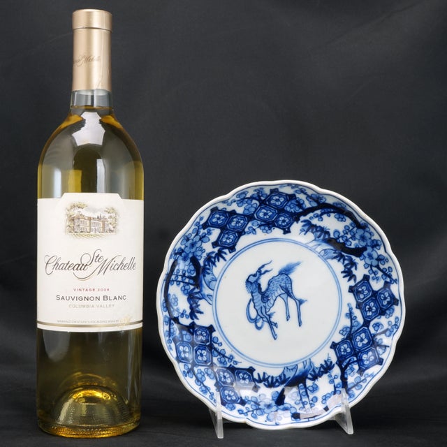 A hand painted porcelain plate with a cobalt under glaze painting of a kirin surrounded by prunus branches in bloom. The...