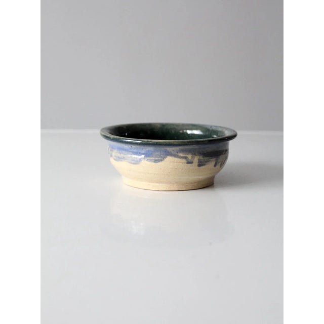 A vintage studio pottery bowl, hand crafted and signed by the artist. The piece features a natural, unglazed exterior...