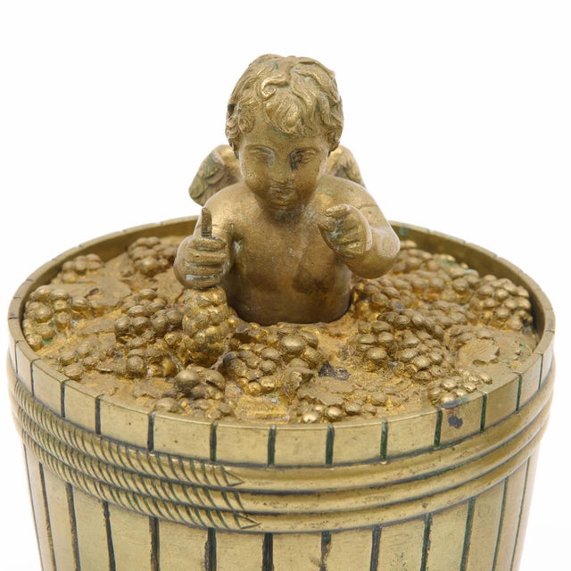 Antique early 19th century French Empire bronze inkwell in the form of a putto making wine in a barrel of grapes. The lid...