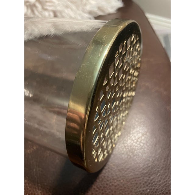 This modern clear glass cylinder vase features a removable gold-tone perforated metal lid, designed in a floral frog style...