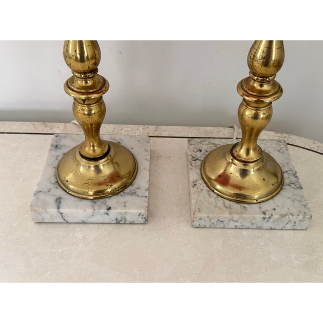 Brilliant pair of vintage cranberry blown glass lamps with ornate brass columns and mounted on marble bases. Circa 1960s....