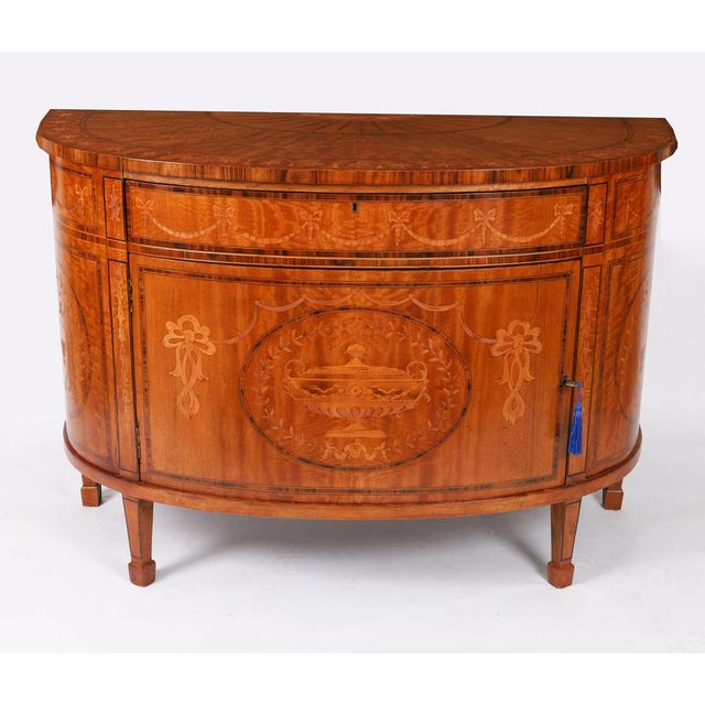 This is a superb antique Sheraton Revival demi-lune satin wood and marquetry cabinet, Circa 1900 in date. The cabinet is...