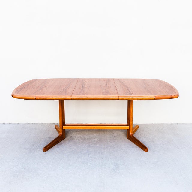 Scandinavian mid century modern expandable teak dining table by D Scan. The surfboard-shaped tabletop rests on a softly...