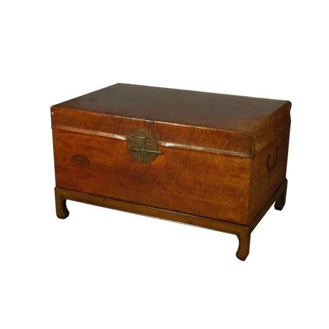 An early 20th-C. Chinese leather trunk with red lacquer finish, original bronze hasp and later hand carved sycamore base....