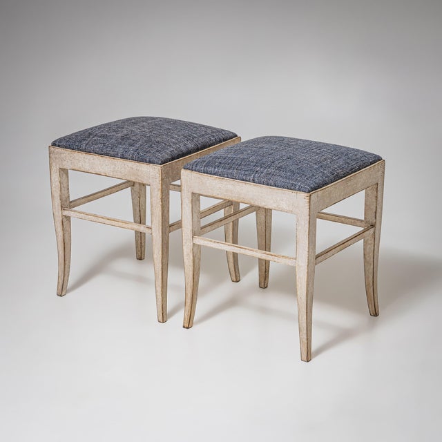 Pair of painted stools with splayed tapered legs and a simple stretcher. Newly upholstered in grey fabric and repainted in...